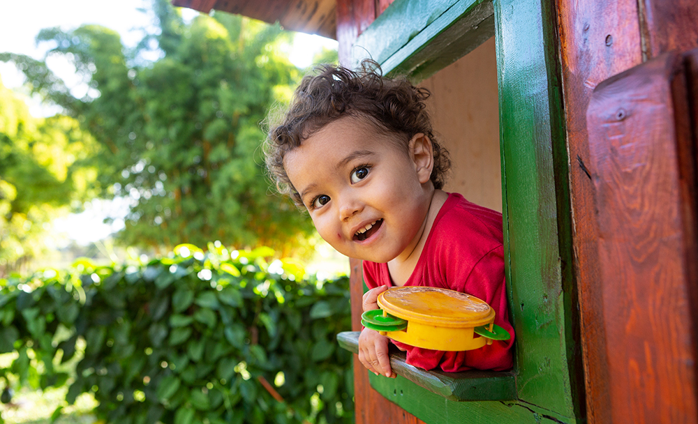 Criança na janela de casinha de madeira