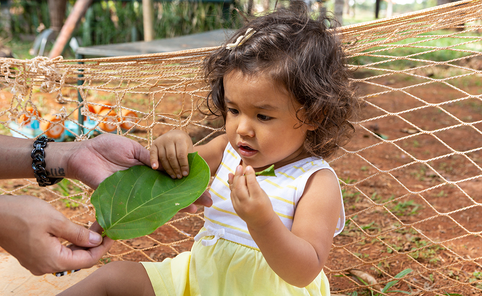Criança ao ar livre brincando com folha
