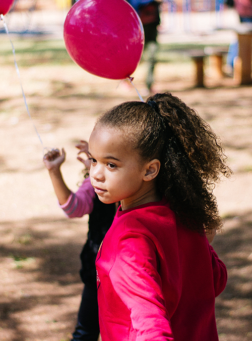 Menina brincando com bexiga em praça